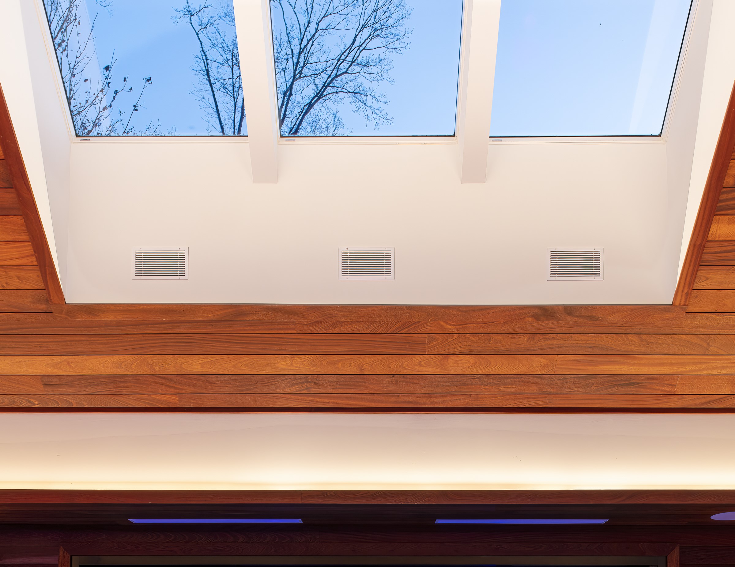 Interior of the DeCoster Pool House, showcasing the wooden ceiling with white skylight boxes. 