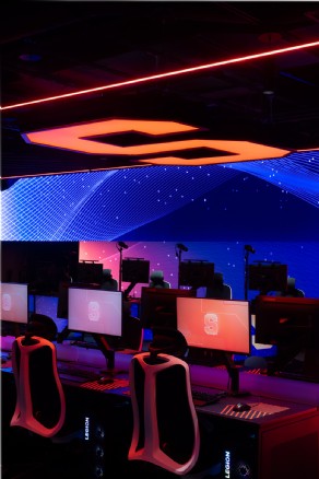 Red and blue esports lighting highlights gaming stations beneath dynamic LED panels at Syracuse University.