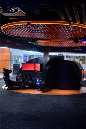 Sim racing pod under orange esports lighting installation at Syracuse University’s esports training facility.